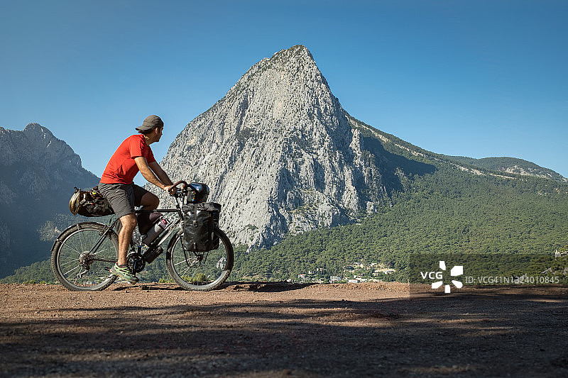 年轻男人在山区骑自行车，主画面的山非常陡峭图片素材