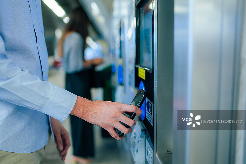 特写：年轻亚洲男人在地铁站使用智能手机非接触式支付购买地铁票图片素材