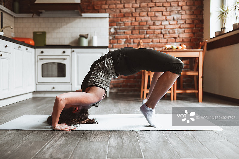 在家里厨房准备做桥式体操运动的漂亮女人图片素材