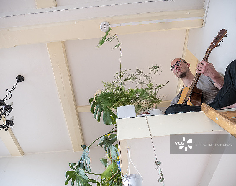 年轻男子在家中宿舍弹吉他的局部照片图片素材