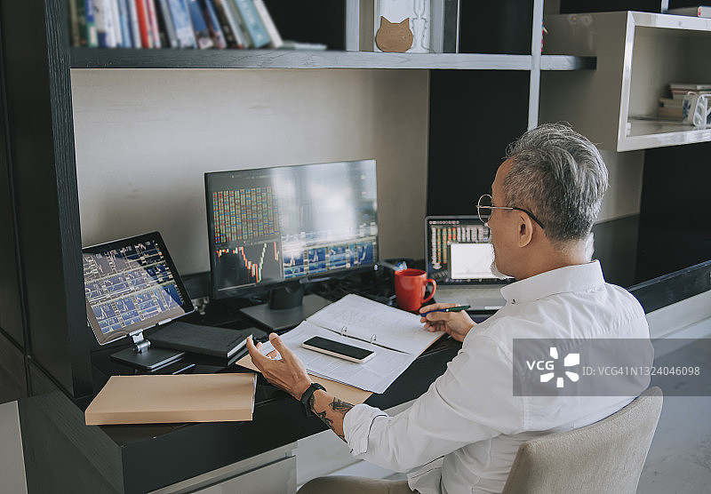 在家工作，监控股市趋势的中国老年男人图片素材