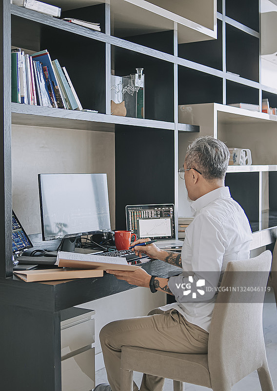 在家工作，监控股市趋势的中国老年男人图片素材
