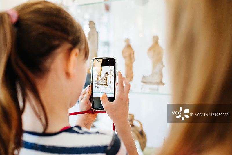 年轻女孩用智能手机拍摄博物馆展品图片素材