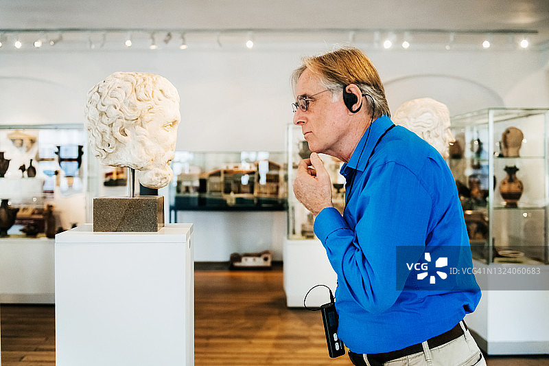 年长的男人在博物馆里专心看着大理石半身像图片素材