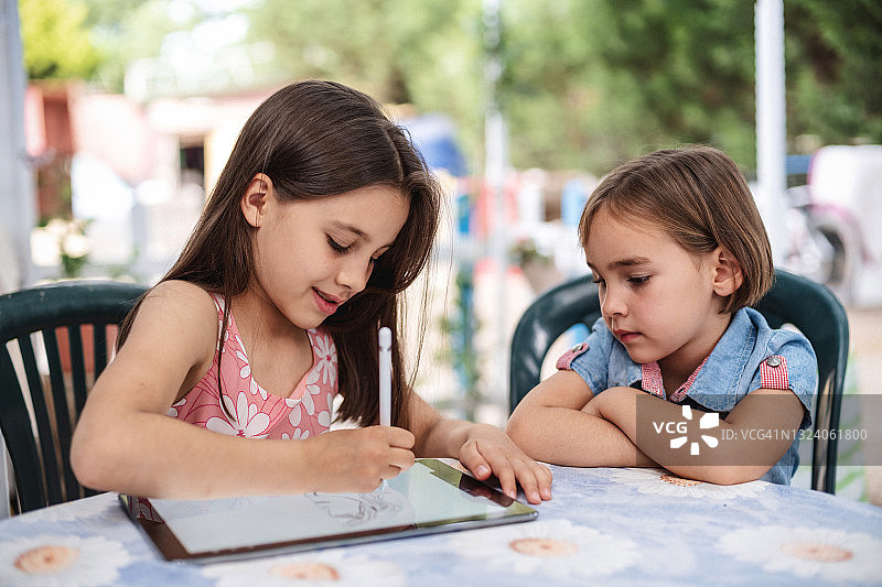 两个快乐的小女孩一起在户外用数位板绘画图片素材
