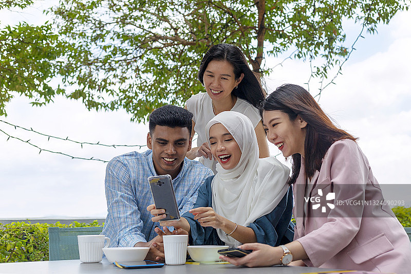 亚洲年轻朋友一起看智能手机图片素材