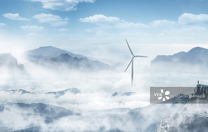 悬崖顶上眺望云海中风力涡轮机的男人剪影图片素材