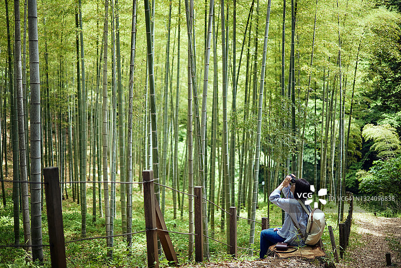 中年妇女在森林里徒步旅行时用双筒望远镜看风景图片素材