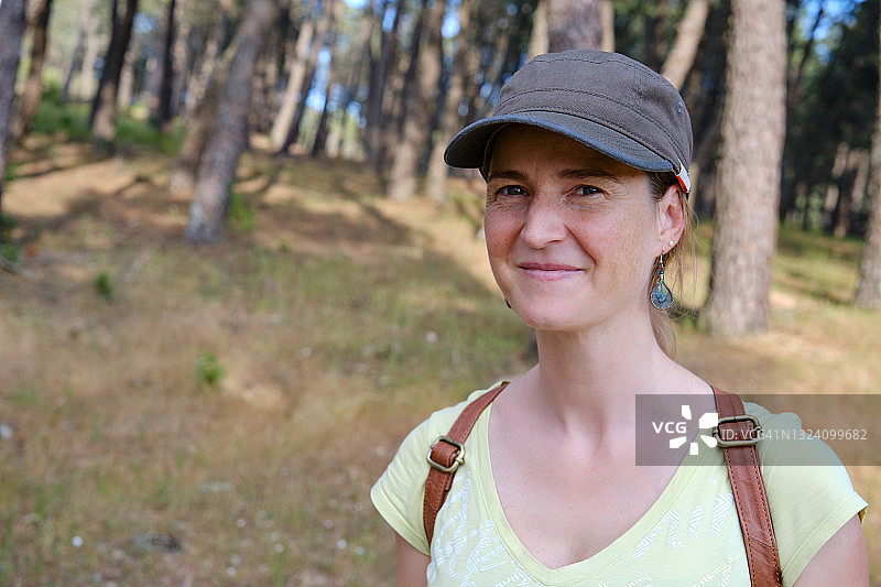 戴着帽子在阳光明媚的森林里行走的女人 портрет图片素材