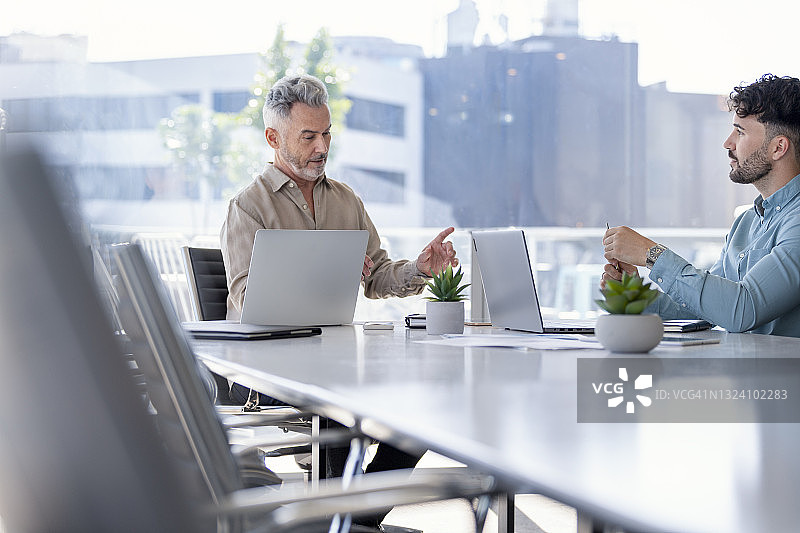 两名使用科技产品的商人，都穿着休闲服装图片素材