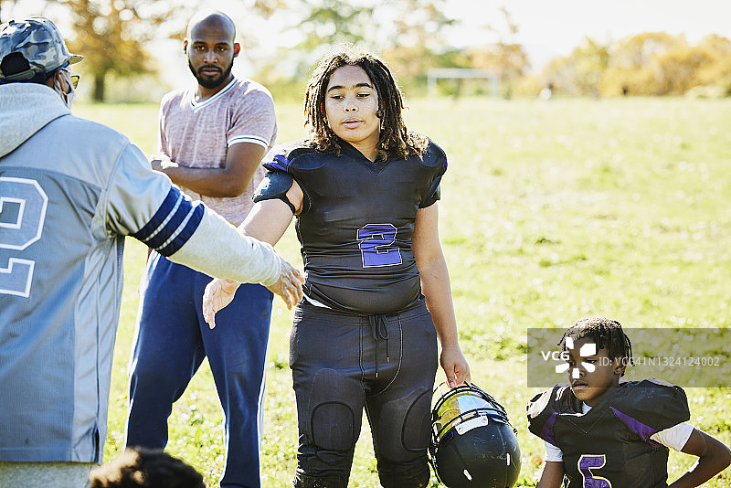 秋日下午，年轻足球运动员赛后与教练握手的中景照片图片素材