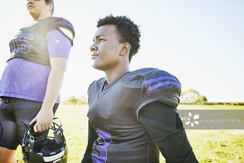 秋日下午，年轻足球运动员在训练后跪在球场上的中景肖像图片素材