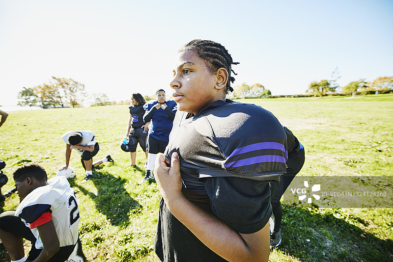 年轻橄榄球运动员在秋日下午训练后站在球场上的中景肖像照图片素材