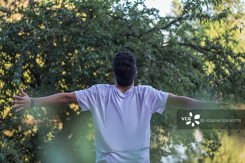 年轻男子张开双臂欣赏日落和自然风光图片素材