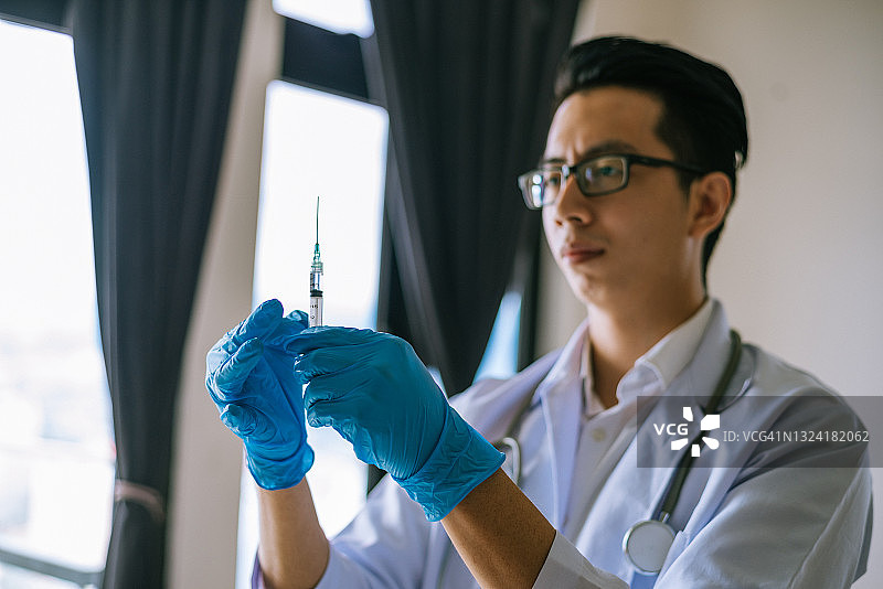 在医院手持注射器的年轻亚洲医生图片素材