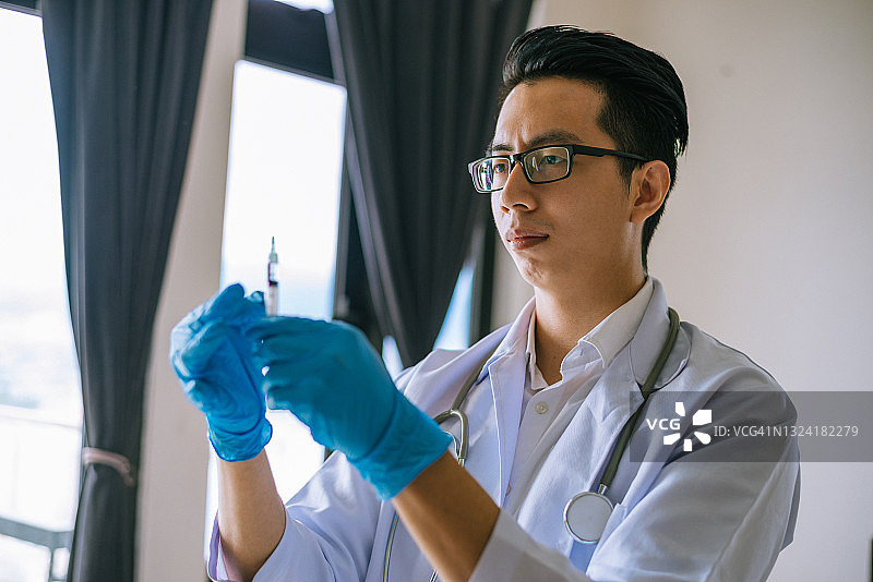 在医院手持注射器的年轻亚洲医生图片素材