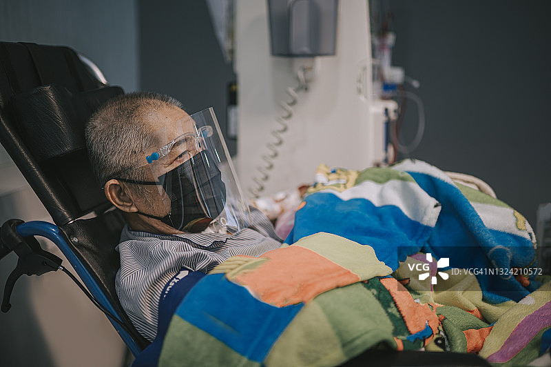 在医院接受透析治疗的华人老年男人，戴着面罩和防护面罩坐在轮椅上图片素材