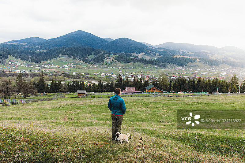 年轻男人和狗在山里享受清新的春天图片素材