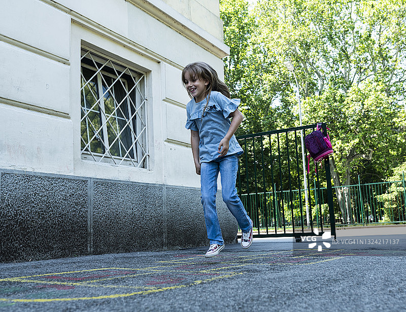 快乐的女学生在玩跳房子游戏图片素材