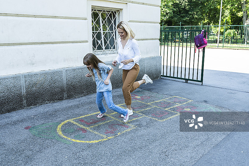 快乐的女学生和妈妈在学校操场上玩跳房子图片素材