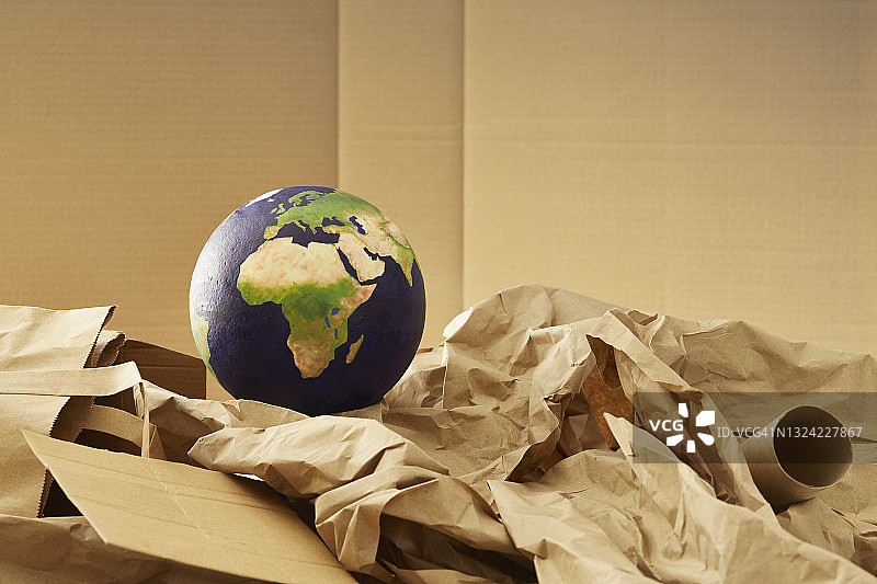 纸质可回收物堆上方的世界地球仪图片素材