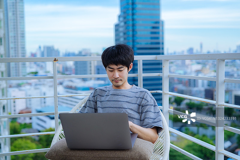早上在阳台上工作的男人图片素材