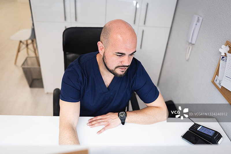 足病医生在他诊所的电脑上查看您的数据图片素材