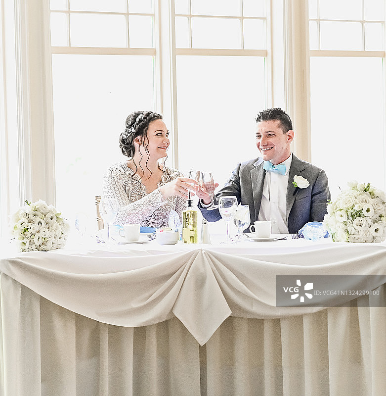 婚礼招待会上，新娘和新郎在主桌用香槟庆祝图片素材