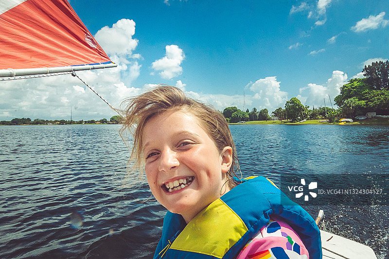 快乐的女孩在夏天自信地在湖上航行的肖像图片素材
