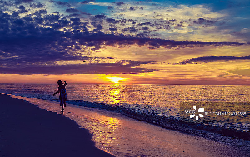 佛罗里达州，田园诗般的日落海滩上，充满欢乐和活力的孩子剪影图片素材