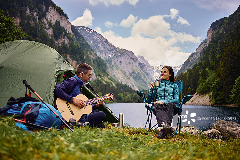 湖边露营弹吉他的年轻男子图片素材