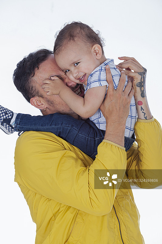 拉丁裔父子肖像：穿着色彩鲜艳的休闲装，调皮地笑着看向镜头图片素材