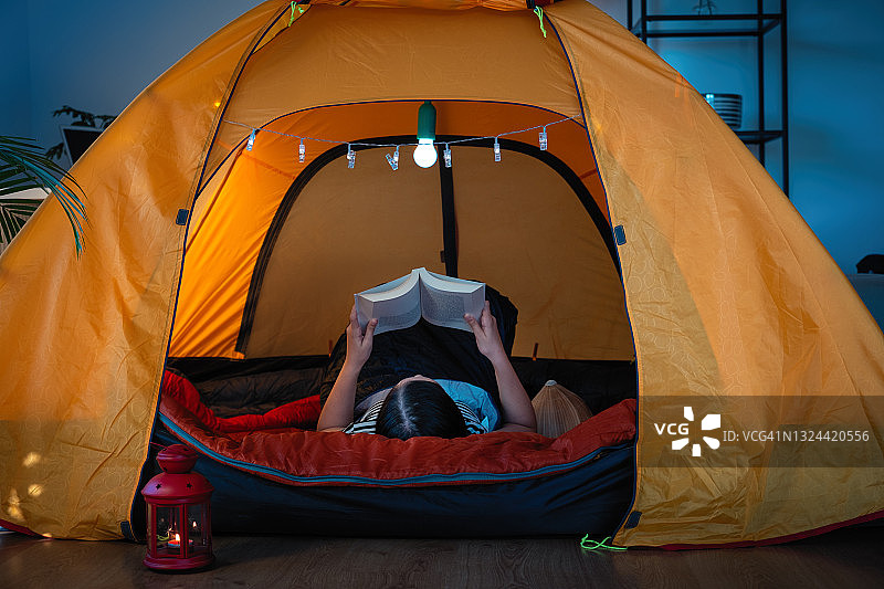 在客厅帐篷里阅读经典书籍的少女图片素材