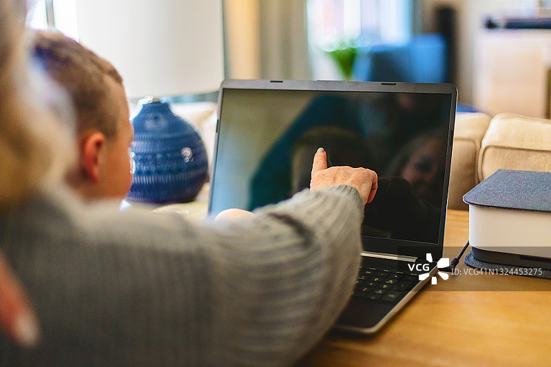 中年祖母与学龄前孙子一起使用笔记本电脑照片图片素材