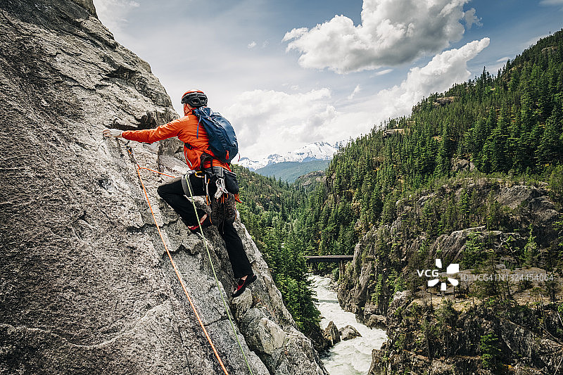 一位男攀岩者在惠斯勒附近的河谷上方攀登岩壁图片素材