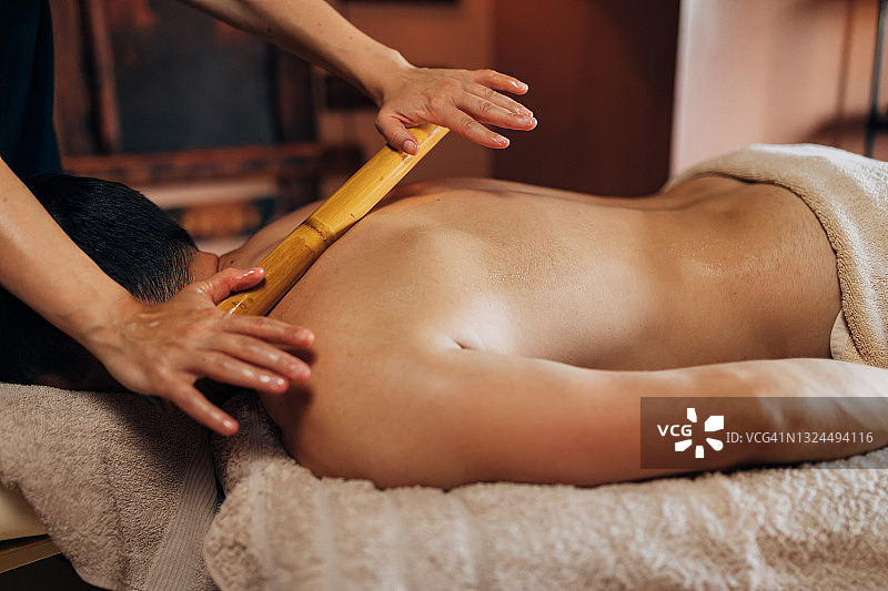 按摩师使用竹筒滚轮放松背部图片素材