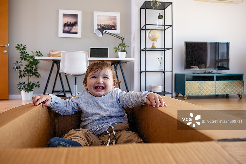 在纸箱里玩耍的可爱男孩图片素材
