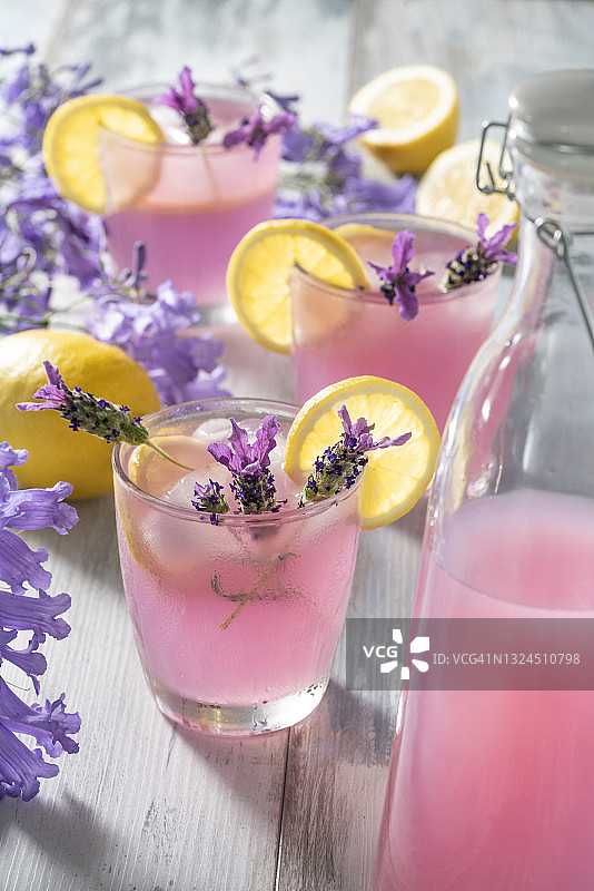 粉色柠檬水，注入薰衣草花，冰块和柠檬片在柔和的彩色背景中图片素材
