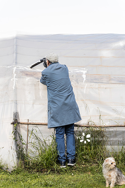 男子用填缝枪用硅胶密封剂修理温室背面图片素材