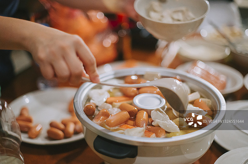 餐桌上，手将食材放入电饭煲（高角度）图片素材