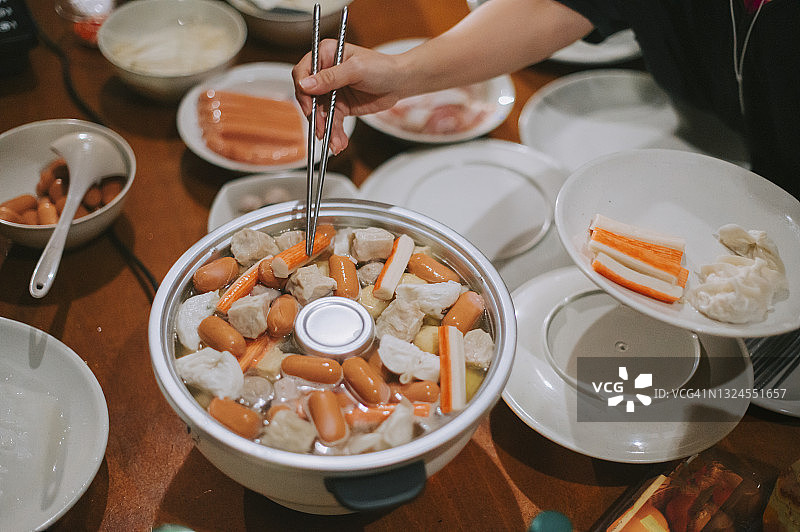 餐桌上，手将食材放入电饭煲（高角度）图片素材