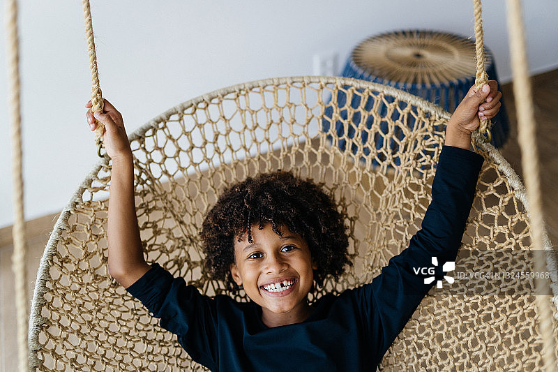 男孩坐在悬挂的椅子上图片素材