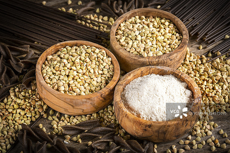 木碗中的全麦荞麦、荞麦面和乡村木桌上的面粉图片素材