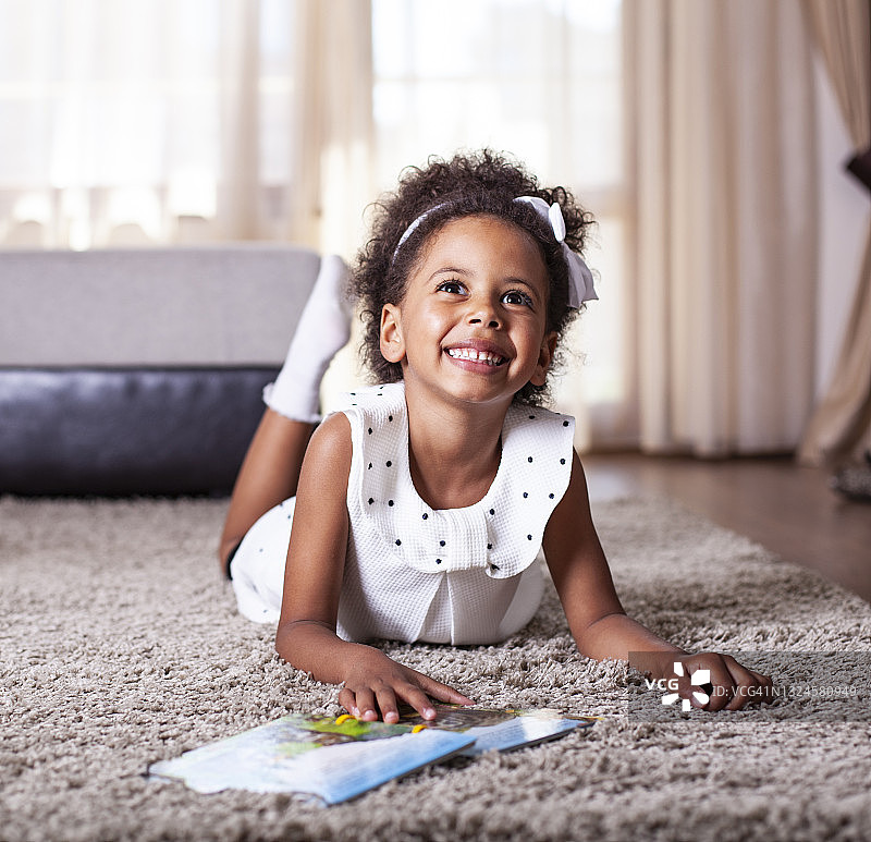 在毯子上看书的可爱小女孩图片素材