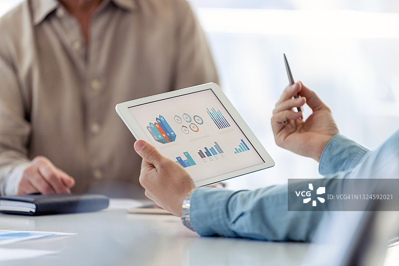商务人士在数字平板电脑上处理财务数据特写图片素材
