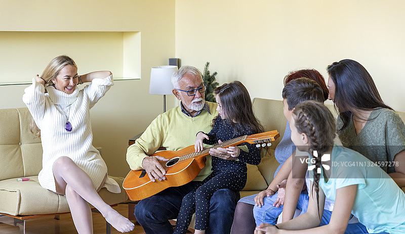 年长的男人弹着吉他，全家享受着音乐的节奏图片素材