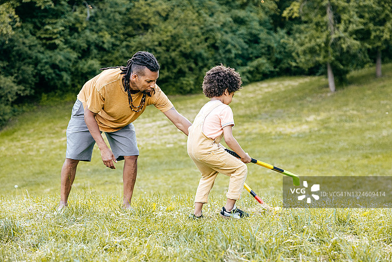 父亲在夏日与幼儿儿子一起打冰球图片素材