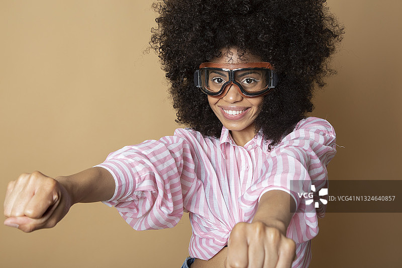 戴着飞扬眼镜的非洲裔女人，米色背景图片素材