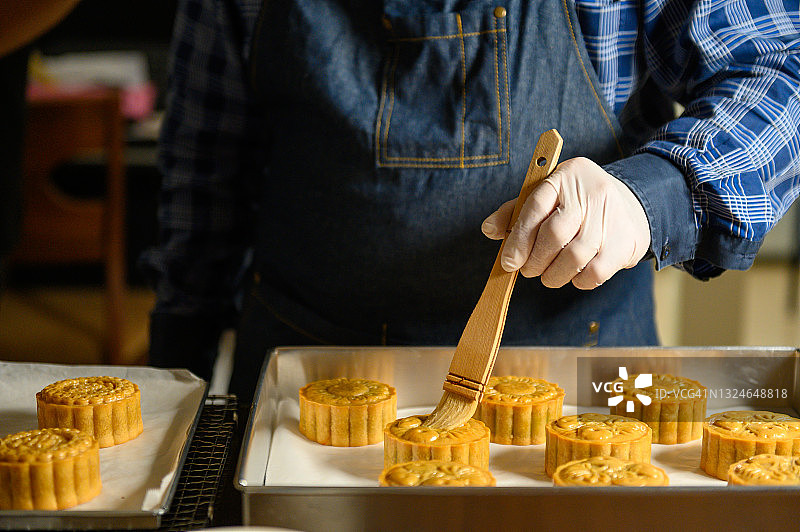 月饼烘焙师在顶部刷蛋液准备烘烤图片素材