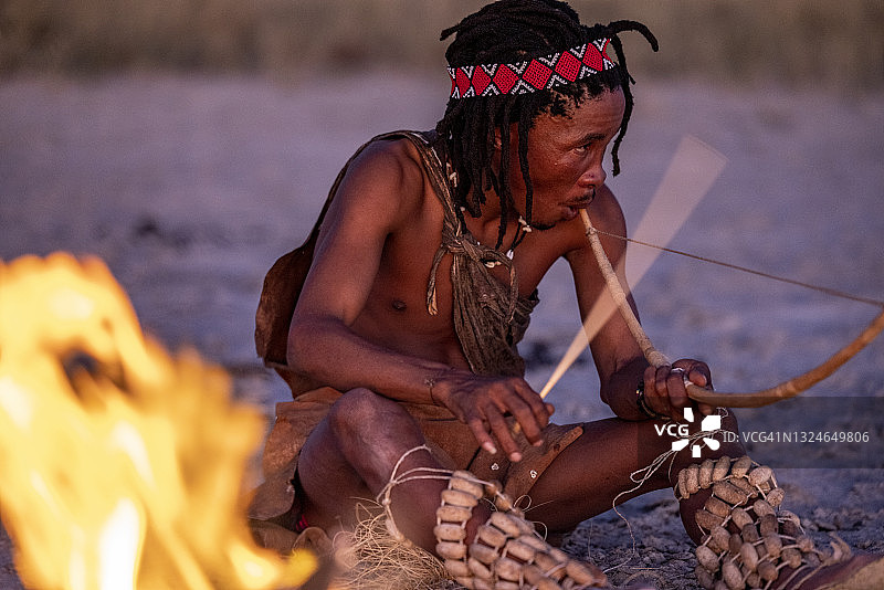 布须曼人在日落时分围着篝火演奏传统乐器的特写图片素材